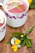 Tassen mit rosafarbener Limonade und Sträußen von Hahnenfuß (Ranunculus) in Brecon, Powys, Wales, UK