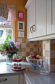 Cupcakes on worktop in kitchen with white fitted units and checked splashback, London home, England, UK