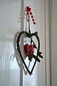 Herzförmiges Ornament mit Mistelzweig an weiß getäfelter Tür in einem Cottage in Shropshire, England, Vereinigtes Königreich