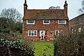 Mittlere erwachsene Frau verlässt freistehendes Cottage in Shropshire, England, UK