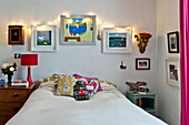 Lichterketten und Kunstwerke über dem Bett mit Wärmflasche in einem Cottage in Penzance, Cornwall, England, UK