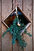 Vogelschmuck mit immergrüner Girlande an der hölzernen Eingangstür eines Hauses in Tregaron, Wales, UK