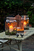 Beleuchtete Kerzen und große Vorratsgläser auf verwittertem Tisch Sherford garden terrace Devon UK