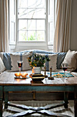 Red wine and candles with cut flowers on coffee table at window of Crantock home Cornwall England UK