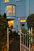 Open gate and lit windows of pebble-dashed Penzance terraced house Cornwall England UK