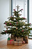 Gift wrapped presents under Christmas tree in Wadebridge home, North Cornwall, UK