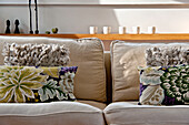 Florale und strukturierte Kissen auf einem Zweisitzer-Sofa in einem Haus in Cornwall, UK