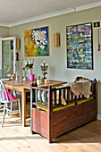 Ausrangierte Sitzbank am Küchentisch mit Kunstwerken im Haus einer Familie in East Grinstead, West Sussex, England UK