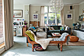 Wooden daybed and large pendant shade in double living room of East Grinstead family home West Sussex England UK