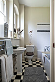Waschbecken in einem schwarz-weiß gefliesten Badezimmer mit grauer Matte in einem Haus in Stamford, Lincolnshire, England, UK