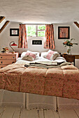 Doppelbett unter dem Fenster in einem Schlafzimmer mit Fachwerk in einem Cottage in Cambridge, England, Vereinigtes Königreich