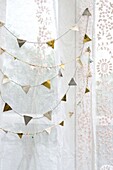 Gold and silver bunting with lace curtains in in London home England UK