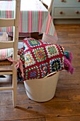 Crochet blanket in plastic bucket Edworth cottage dining room Bedfordshire England UK