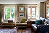 Cremesessel mit braunem Ledersofa im Wohnzimmer von Edworth cottage Bedfordshire England UK