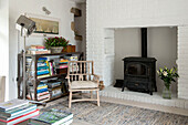 Holzstuhl mit Bücherregal und Kaminofen in einem Bauernhaus in Penzance, Cornwall, England