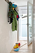 Coats and boots with fishing net in open doorway of family townhouse Cornwall England UK