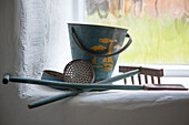 Bucket and spade with rake and sieves on whitewashed windowsill Cornwall UK