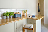 Bar stool at worktop with breadbin and herbs in St Ives kitchen Cornwall UK