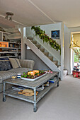 Lit candles on coffee table with striped sofas in open plan living room with staircase in Penzance farmhouse Cornwall UK