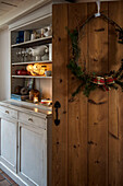 Christmas wreath on wooden door with kitchen dresser in St Erth cottage Cornwall UK