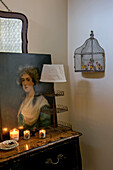 Lit candles and oil painting with vintage lamp on sideboard in London home UK