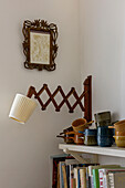 Retractable wall lamp with vintage cups and books on shelves in London home UK