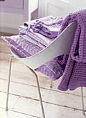 Bedroom chair with a folded pile of purple fabrics