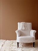 Budget Style room close up with vintage armchair covered in recycled linen and brown paper wallpaper