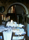 Candlelit festive dinner table set with plates napkins and glasses with themed feather table decorations