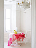 Table with cloth and chandelier in bright panelled room
