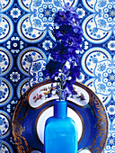Blumen in Vase mit blauem und weißem Dekoteller und Tapete