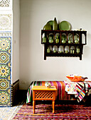 Wall mounted shelf with green ceramics above daybed in Moroccan riad North Africa