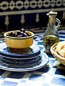 Black olives in ceramic bowl with blue and white plates and vinaigrette Morocco North Africa