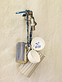 Tassen und Krüge hängen am Wasserhahn in einem spanischen Innenhof