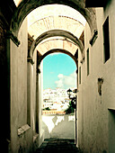 View through arched alleyway to hillside community Spain