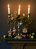 Lit candles and ivy on gold mantlepiece