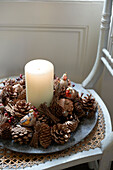 Candle and pine cones on wicker chair seat