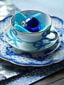 Blaue Christbaumkugel in Vintage-Tasse mit Untertasse