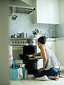 Woman kneeing on cushion while cleaning oven