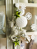 Glittery reindeer and bauble with stars on glass cabinet with snowflakes