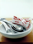 Set of measuring spoons with red and white 'NOEL' ribbon on dish