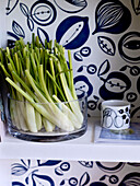 Pak choi in glass bowl with blue and white wallpaper on shelf
