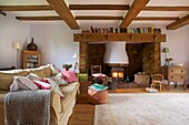 Book storage on mantelpiece above lit wood burning stove in living room of Cranbrook family home, Kent, England, UK