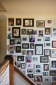Extensive display of family photographs on staircase in Cranbrook home, Kent, England, UK