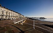 Häuser am Meer und Promenade mit Kiesstrand und entferntem Pier in St Leonards on Sea, East Sussex, England, UK