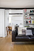 Brown leather sofa and storage shelves in white interior of timber framed house