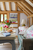 Cut flowers on kitchen table with floral patterned cushions in Sandhurst cottage, Kent, England, UK