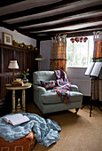 Light blue armchair with blanket and music stand in corner of Sandhurst cottage, Kent, England, UK