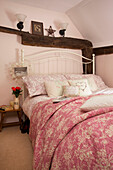 Rosa geblümte Bettbezüge im Schlafzimmer im Dachgeschoss von Egerton Cottage, Kent, England, UK