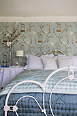 Cut flowers at bedside in light green bedroom of Tenterden home, Kent, England, UK